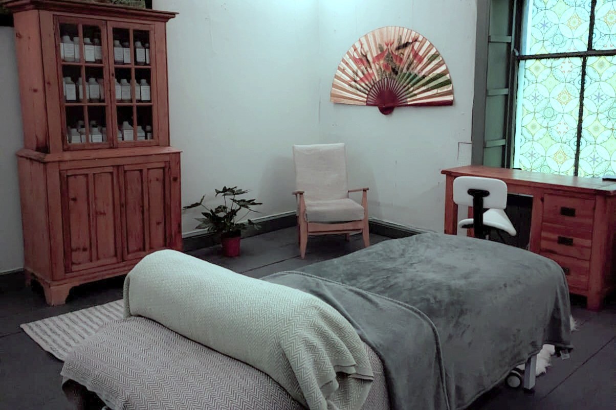 The treatment room, couch made up with blankets, apothecary dresser and stained glass window
